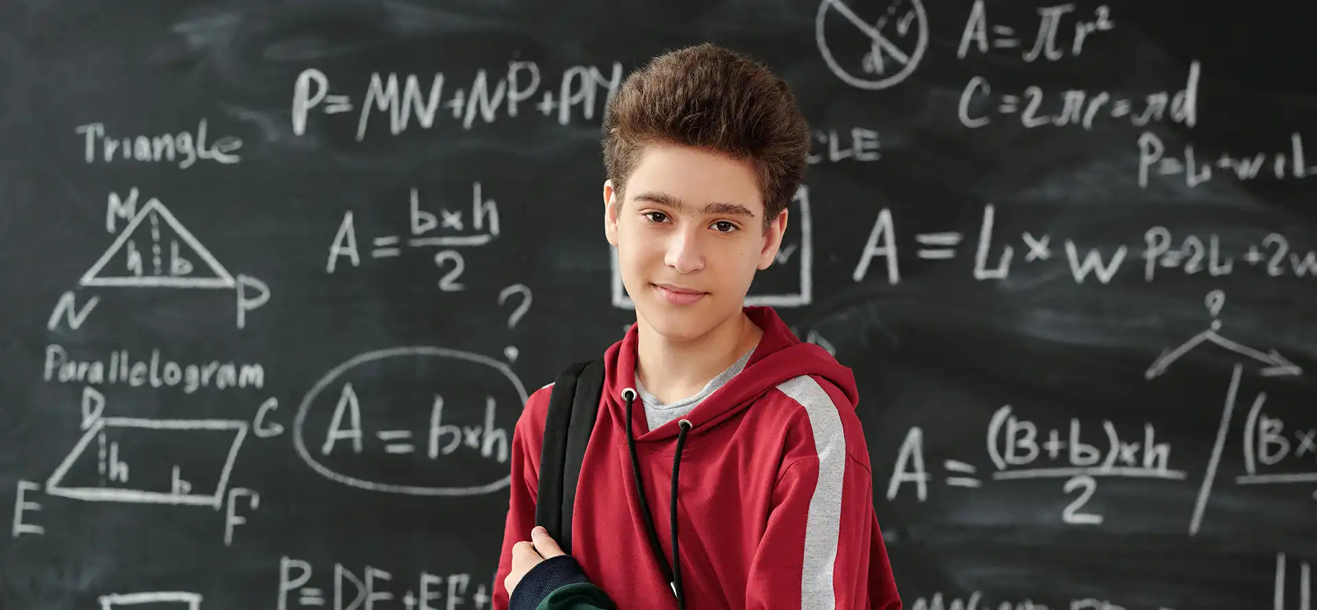 Teenage boy in front of chalk board with math problems